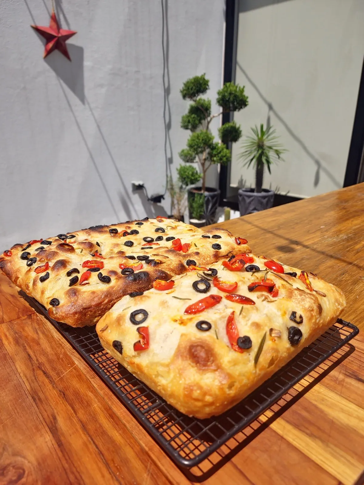 Dos focaccias con jitomate cherry, aceituna y romero sobre una rejilla